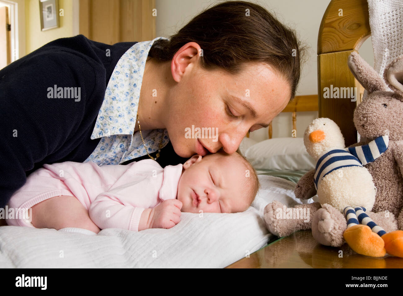 Madre baciare / baci dormire / addormentato new born baby, sul letto / culla. Foto Stock