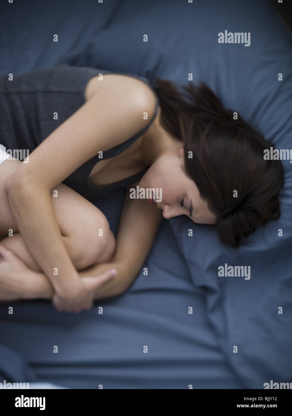 La donna nel letto avvolto a ricciolo Foto Stock