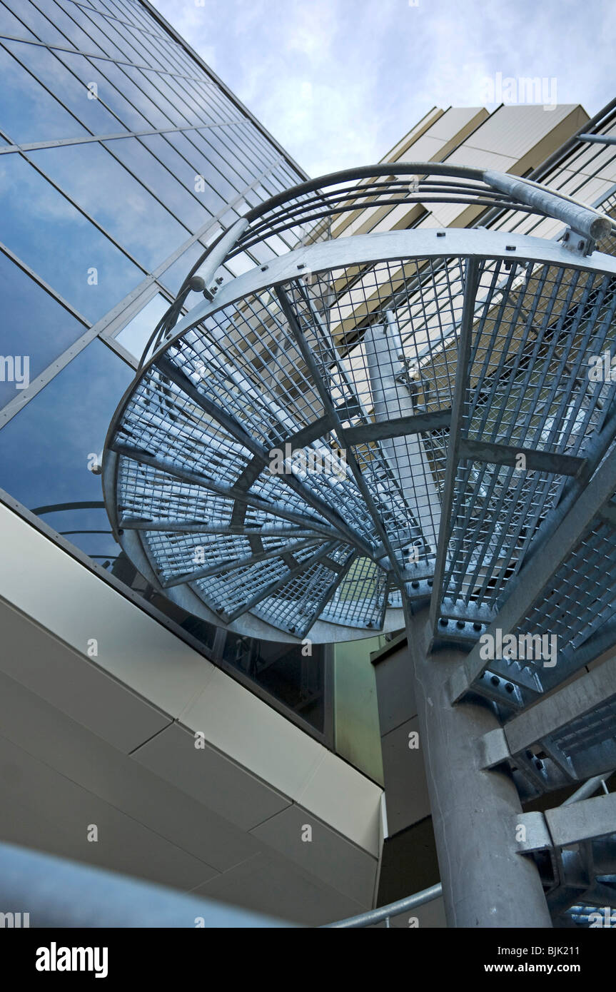 Scala a spirale fatta di metallo sulla facciata di vetro Foto Stock