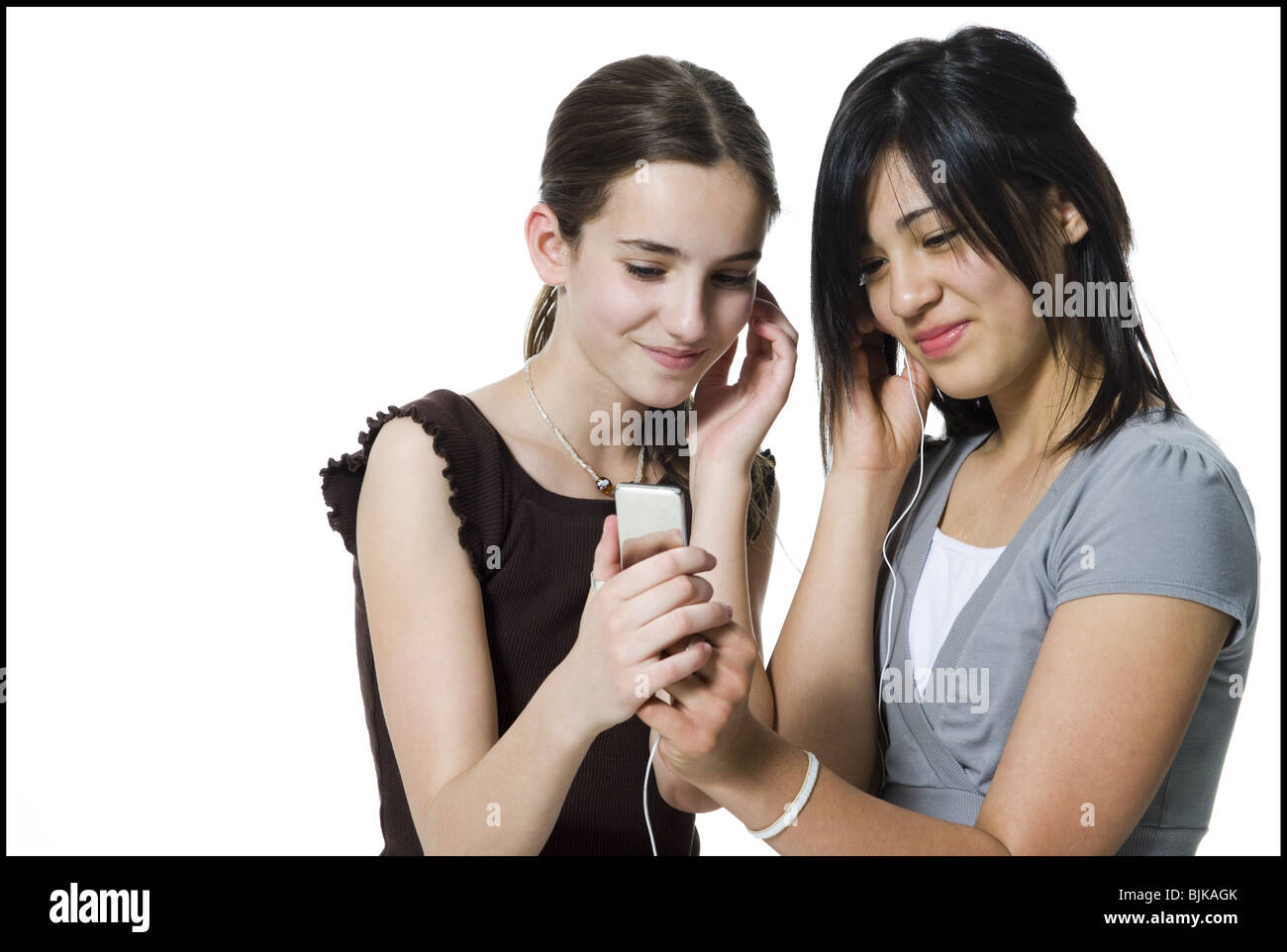 Due ragazze ascoltando mp3 player sorridente Foto Stock