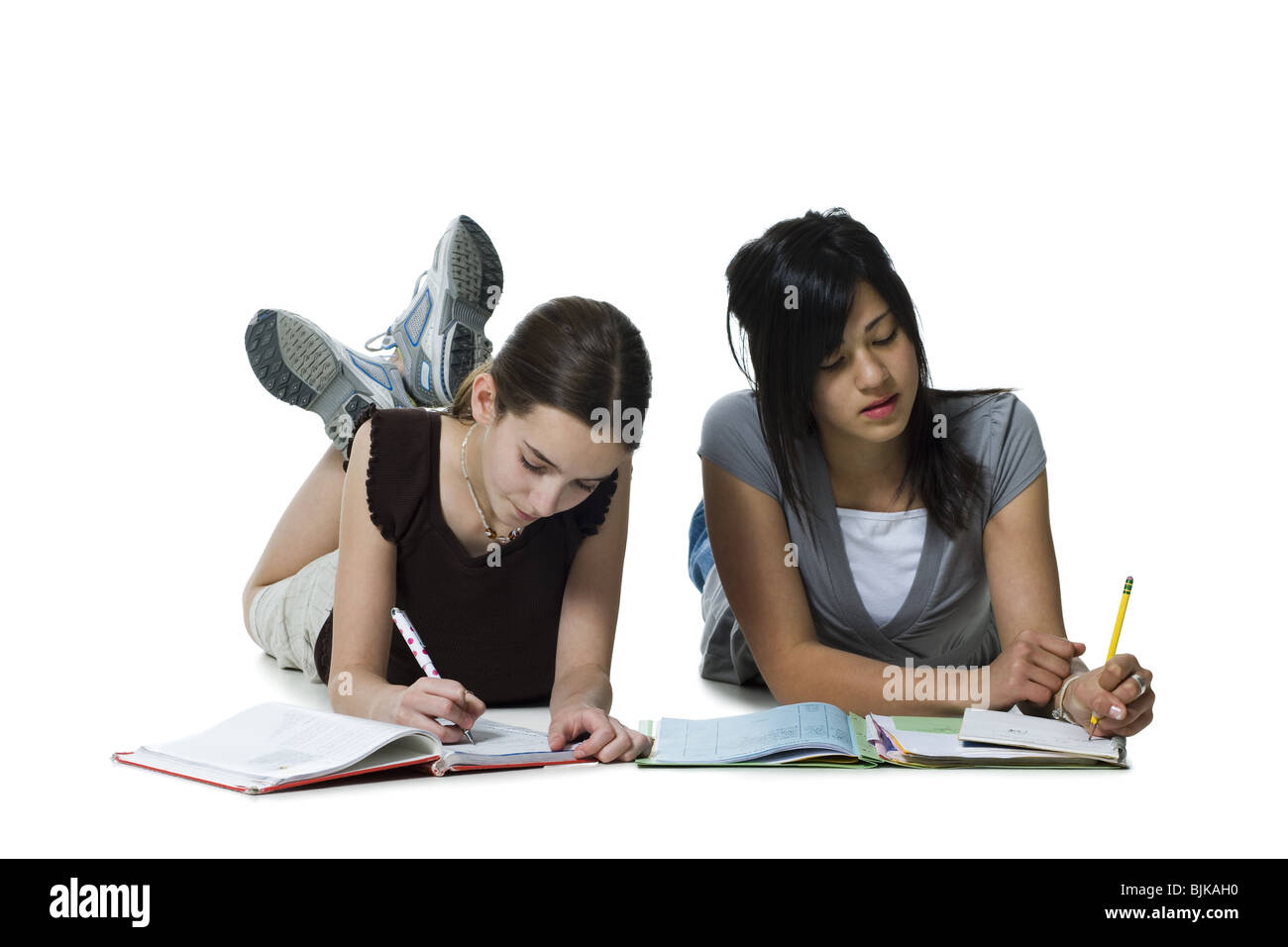 Due ragazze sdraiato facendo i compiti di scuola Foto Stock