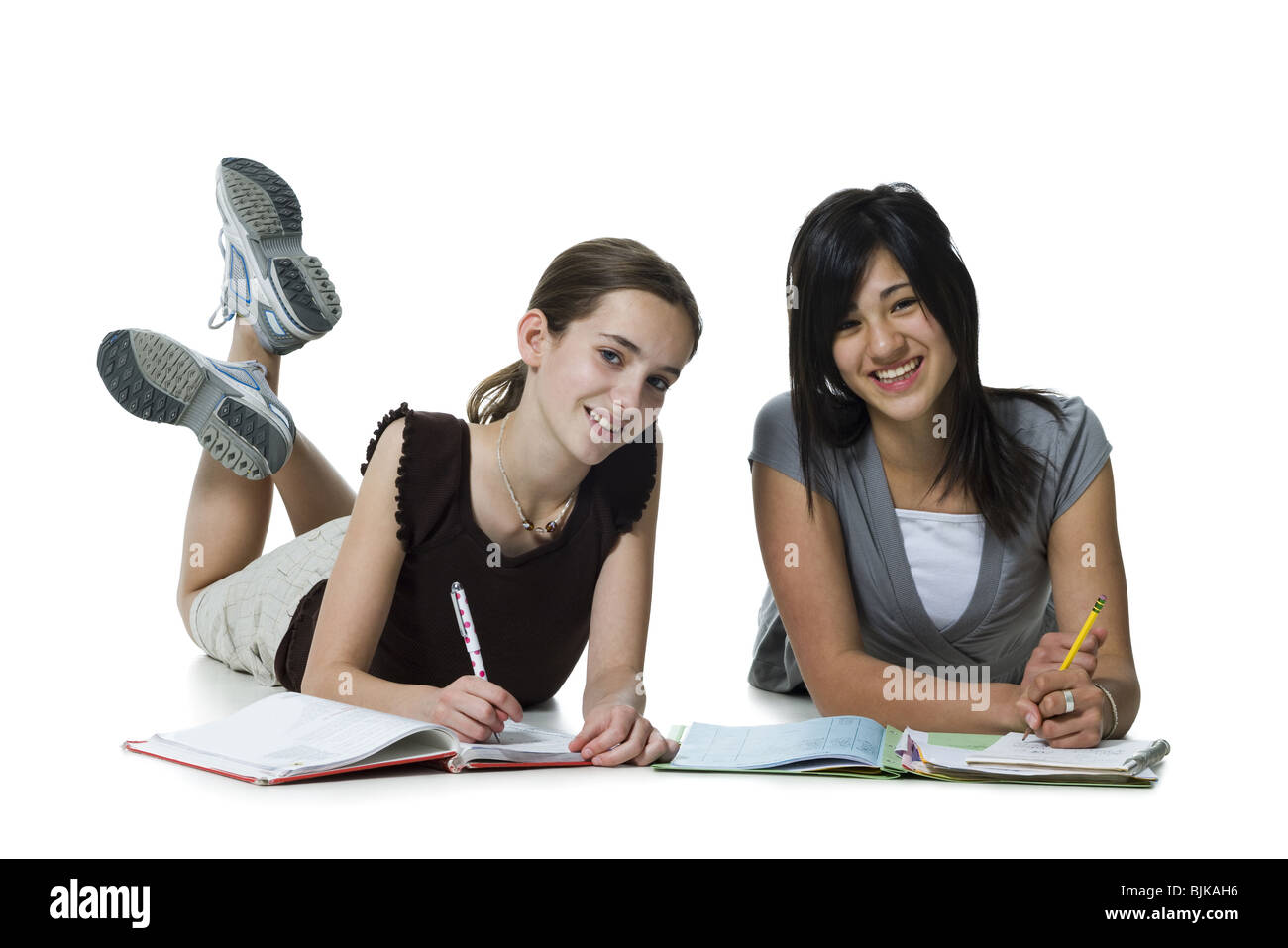 Due ragazze sdraiato facendo i compiti di scuola Foto Stock
