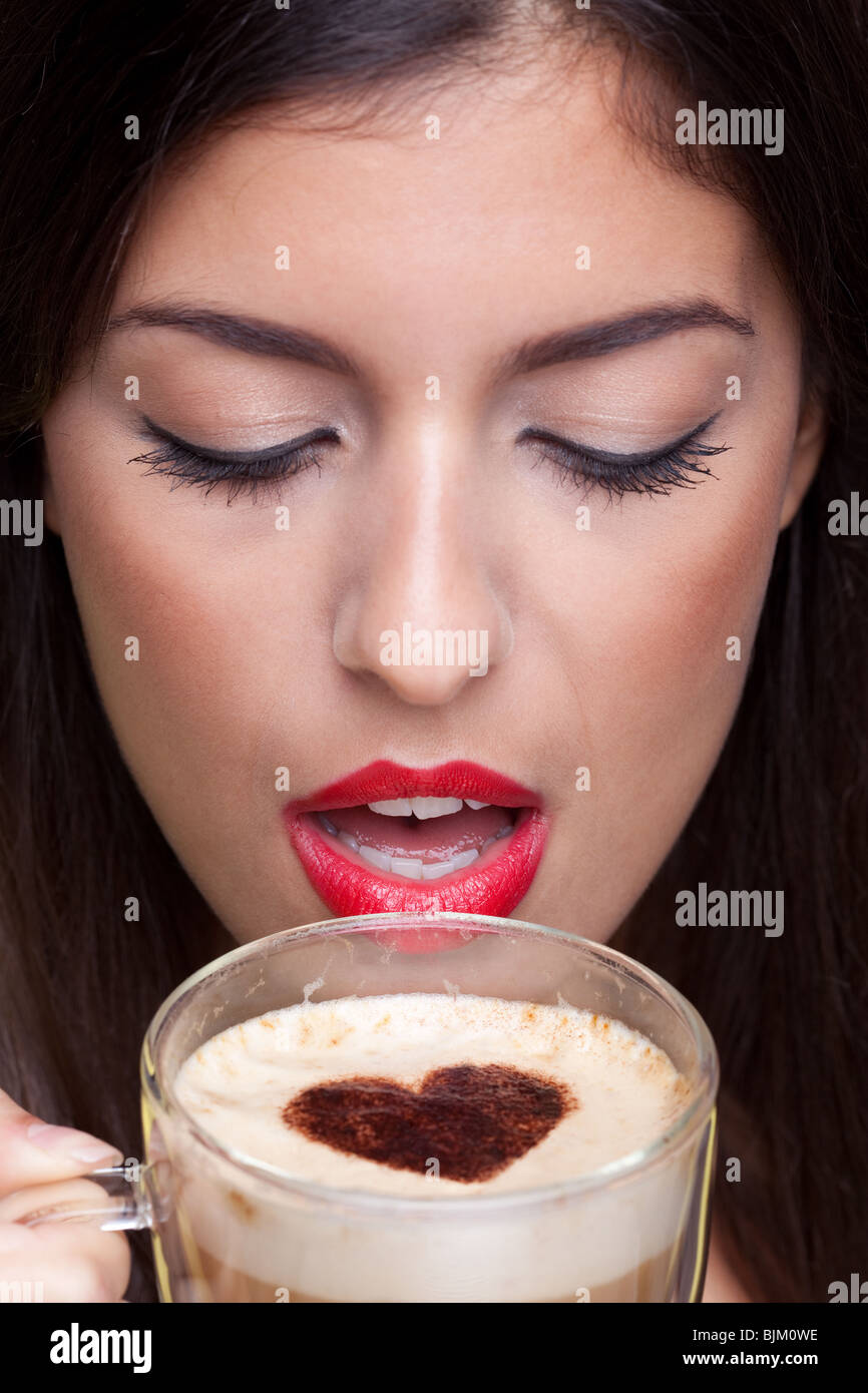 Donna bere un cappuccino con un amore forma di cuore sprinking sulla parte superiore. Foto Stock