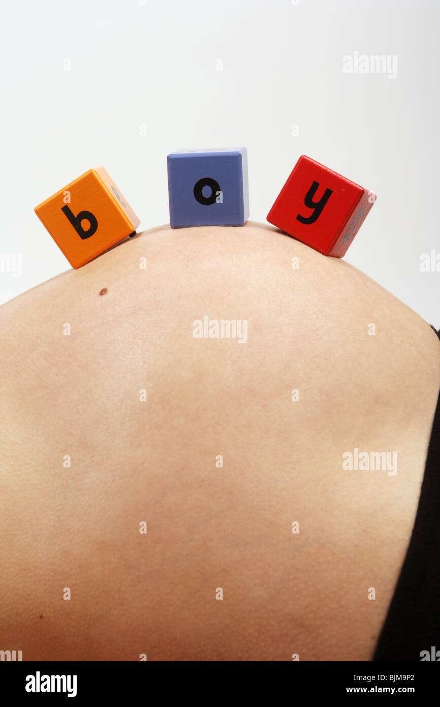 Nove mesi di gravidanza della donna sdraiata sulla schiena con il giocattolo di legno blocchi sul suo ventre ragazzo di ortografia Foto Stock
