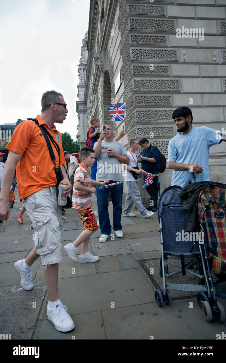 Un mam da arancio a piedi a Londra affronta un uomo asiatico Foto Stock