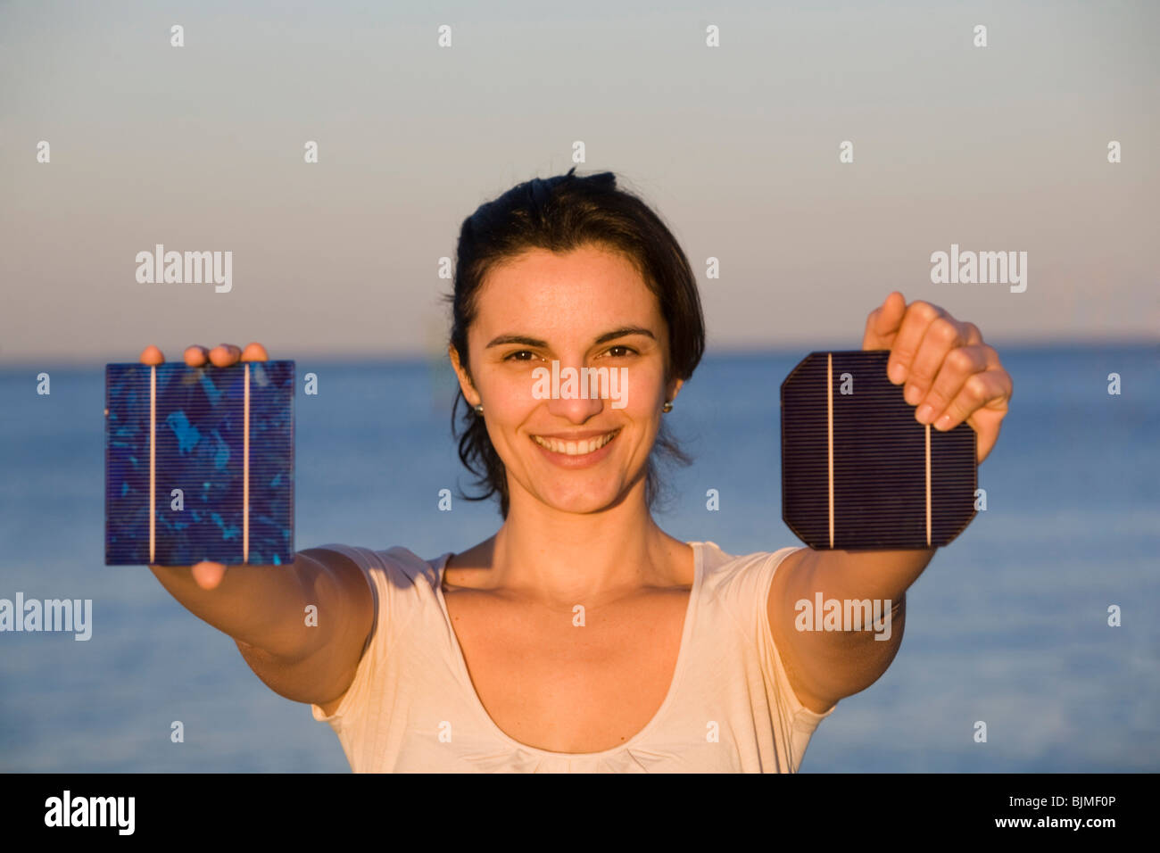Donna che mantiene un pannello solare verso il sole Foto Stock