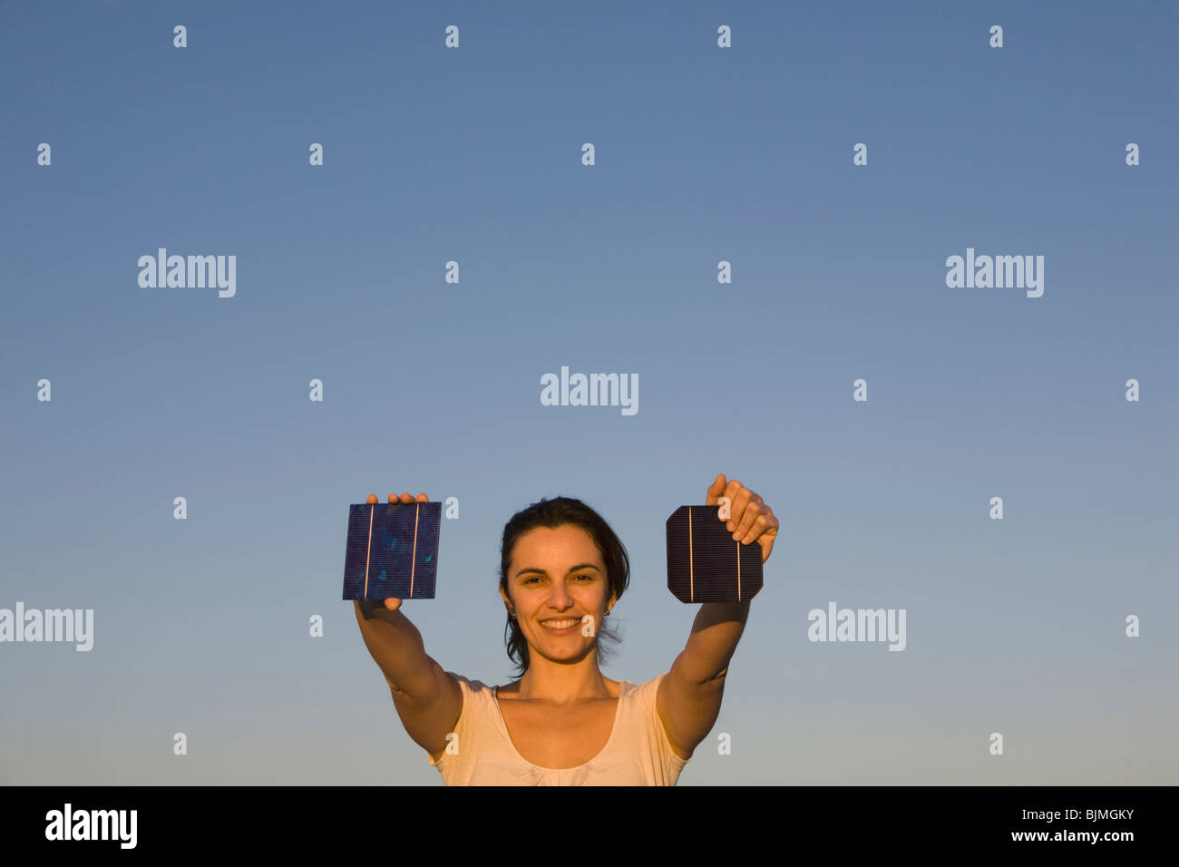 Donna che mantiene due pannelli solari verso il sole Foto Stock