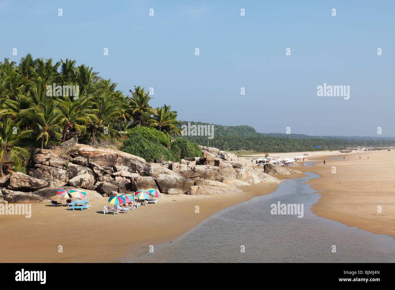 Sedie a sdraio e ombrelloni nella parte anteriore delle palme, Somatheram Beach, a sud di Kovalam, Malabarian Costa, il Malabar, Kerala, India, come Foto Stock