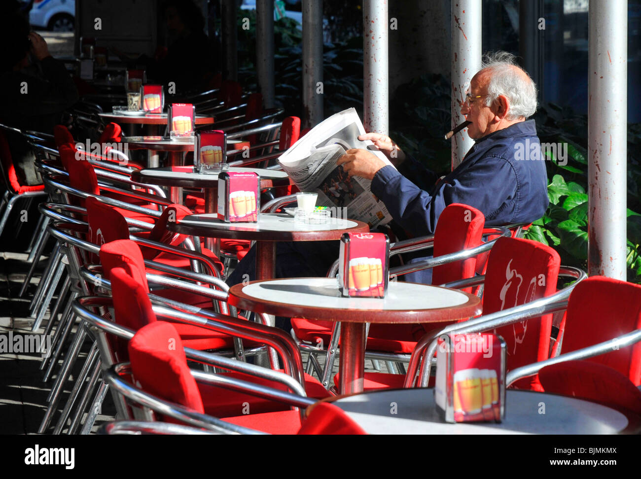 Uomo di fumare un sigaro e la lettura di un quotidiano a un cafe Foto Stock