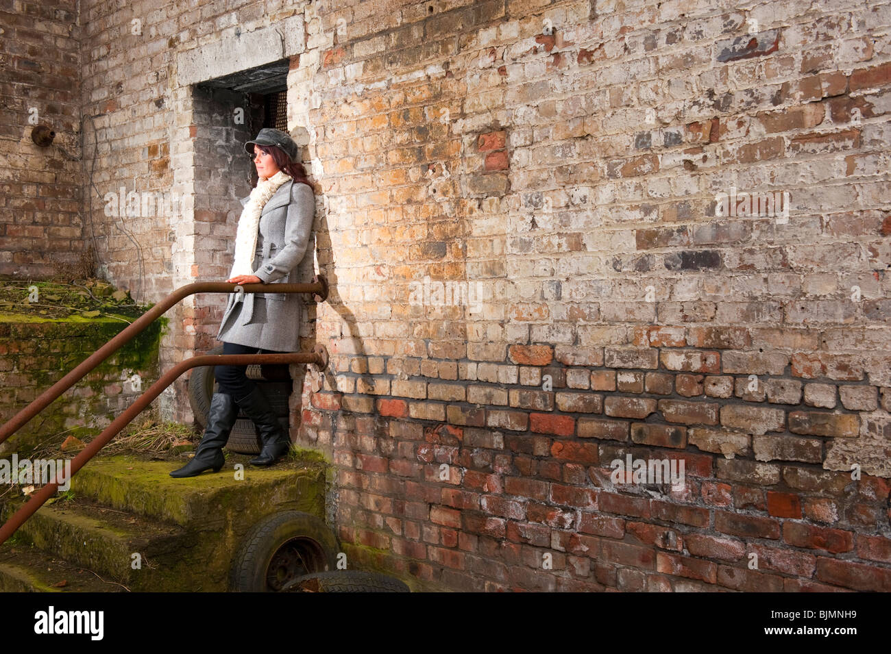 Modello femminile in cappotto invernale contro un muro di mattoni. Modello completamente rilasciato Foto Stock