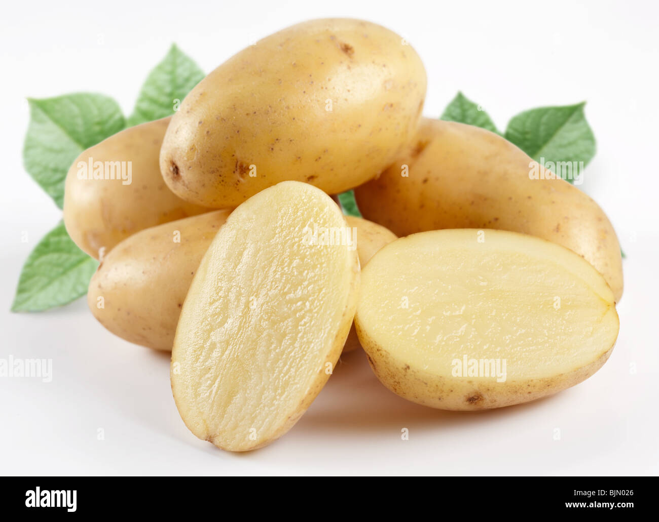 Patate gialle con foglie su sfondo bianco Foto Stock