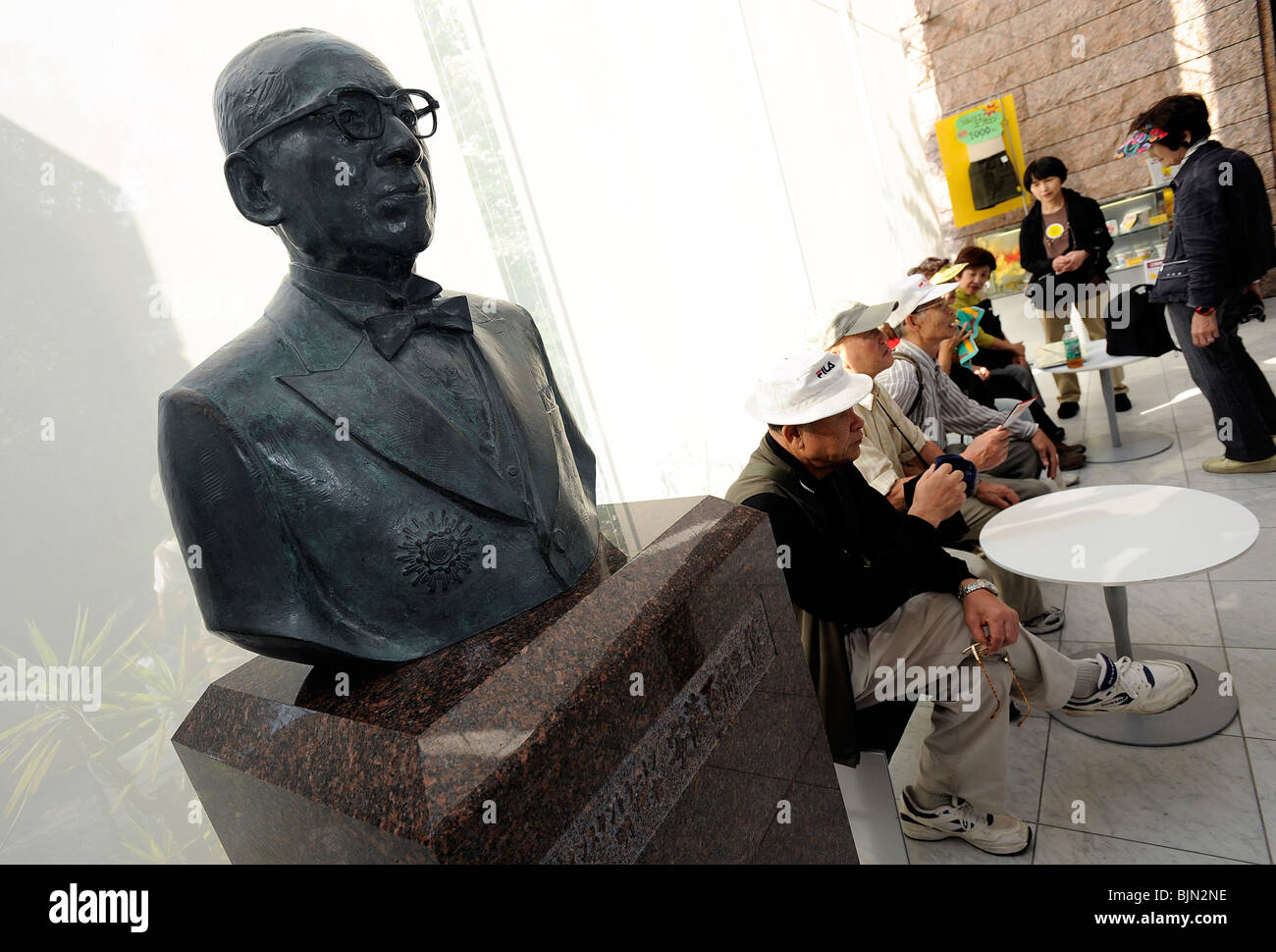 I visitatori prendere un periodo di riposo accanto a un busto di instant noodle inventore Momofuku Ando in Osaka Foto Stock