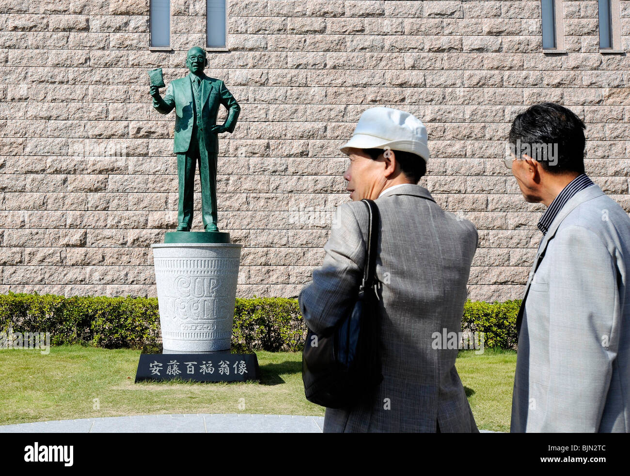 Visitatori guardare una statua di instant noodle inventore Momofuku Ando fuori Momofuku ando Museum in Osaka Foto Stock