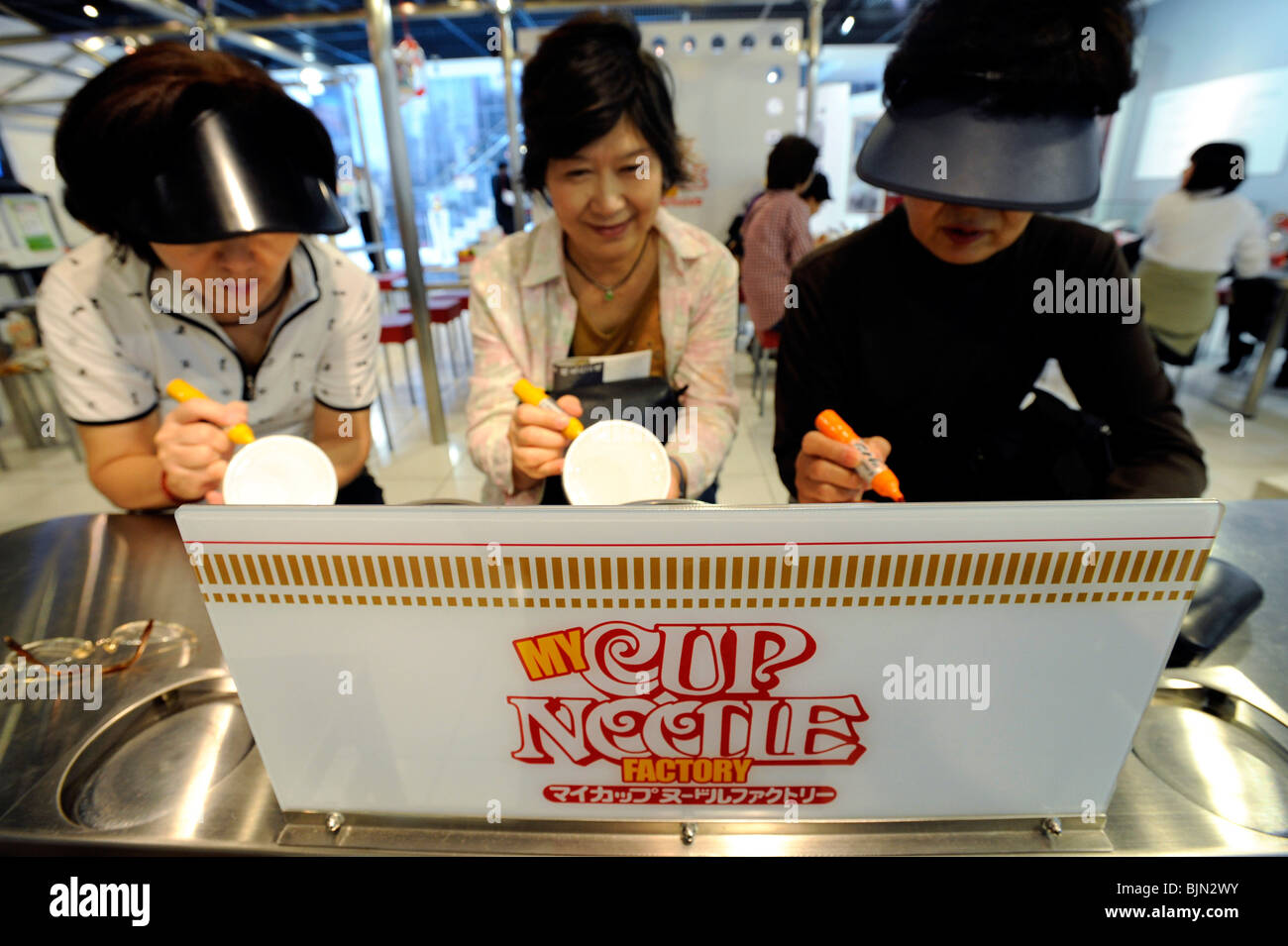 Tre donne di progettare i propri originali bicchieri di noodle all'Momofuku Ando Instant Ramen (noodle) Museum Foto Stock