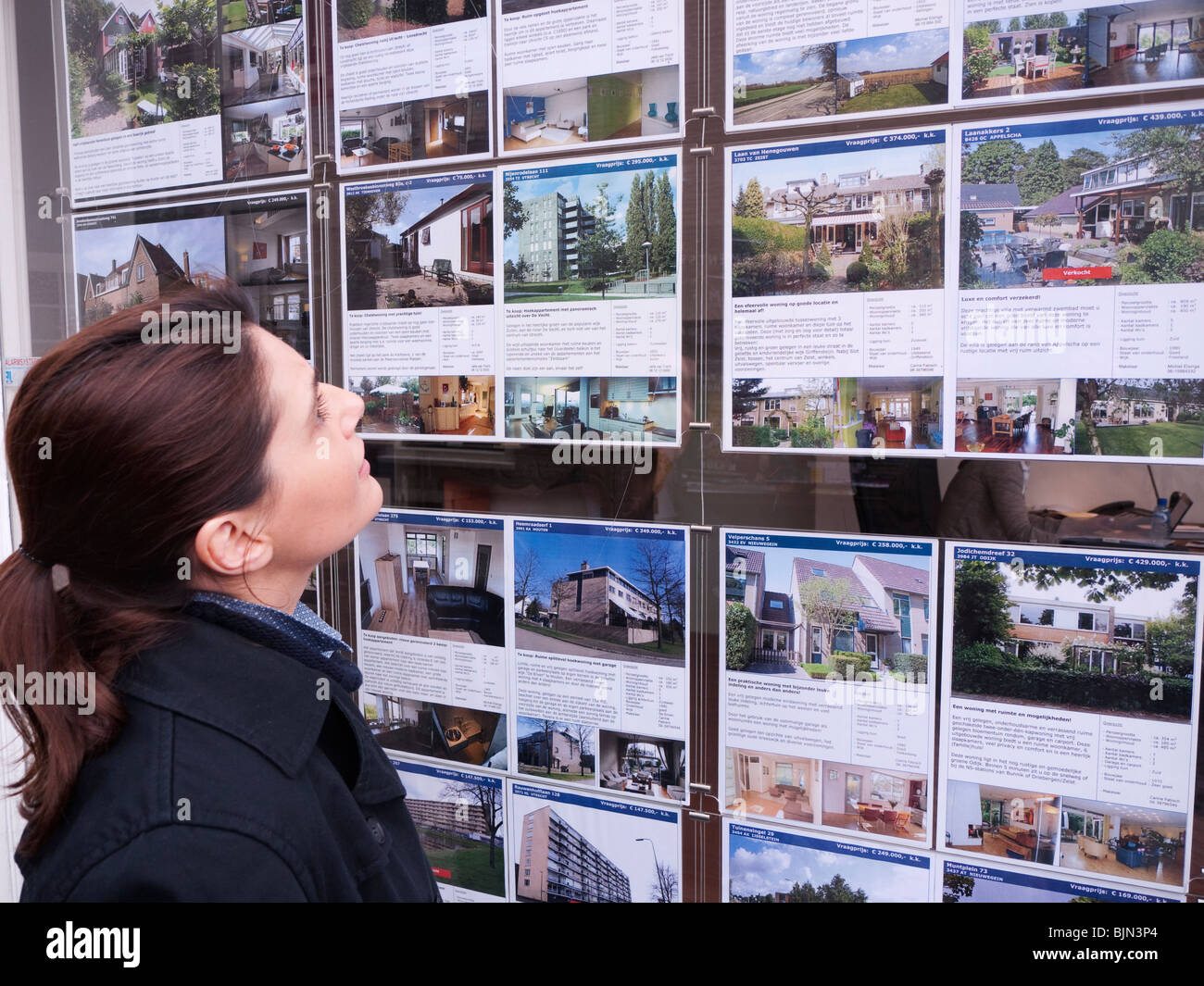 Donna che guarda case in vendita in agenti immobiliari finestra in Utrecht nei Paesi Bassi Foto Stock