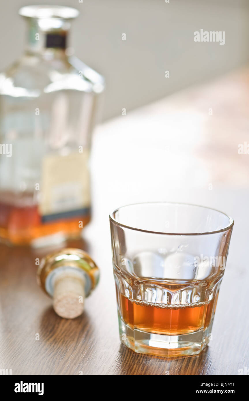 Bicchiere di whiskey e la bottiglia sul contatore di legno Foto Stock