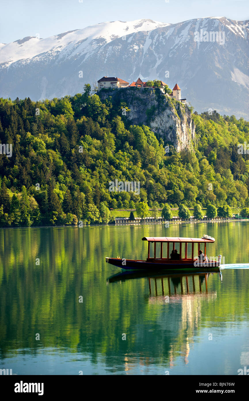 Il lago di Bled con il castello di Bled e una a fondo piatto boat chiamato un Pletna. Bled Slovenia. Foto Stock