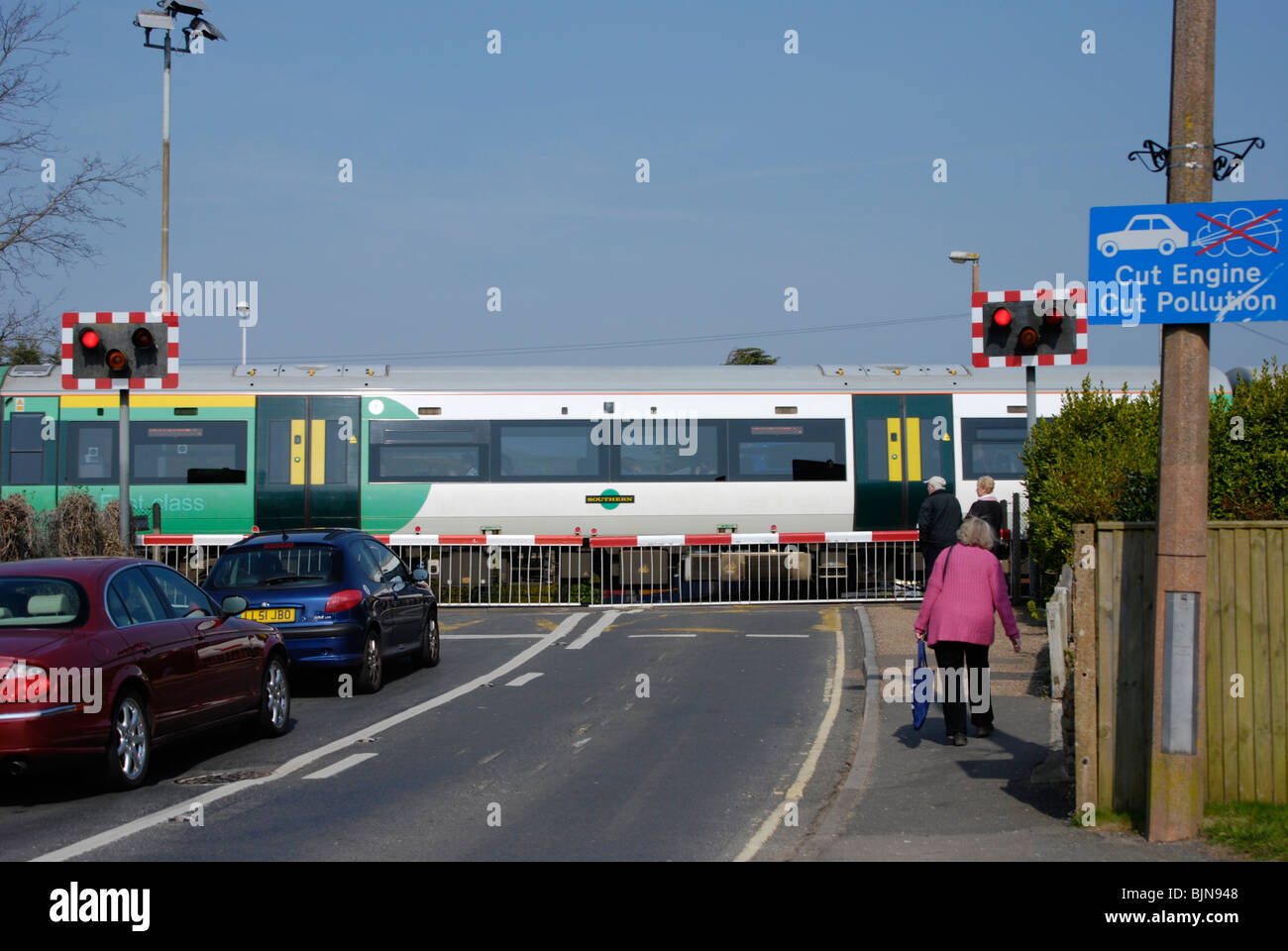 Costruzione di traffico con il passaggio a livello ferroviario barriere verso il basso con un treno accelerando attraverso Foto Stock