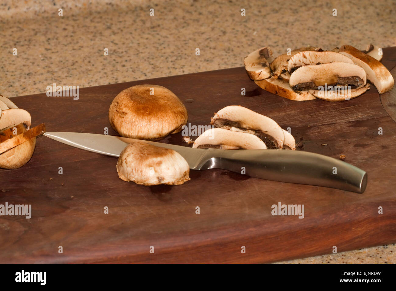 Trinciatura di piccoli funghi champignon Foto Stock