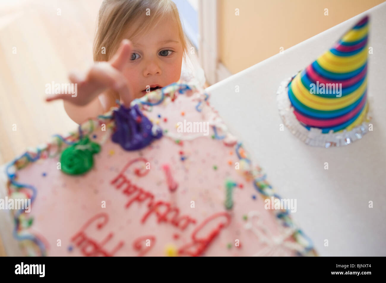Ragazza di toccare la torta di compleanno Foto Stock