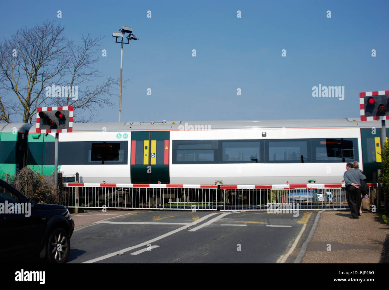 Passaggio a livello ferroviario barriere verso il basso con un treno accelerando attraverso Foto Stock