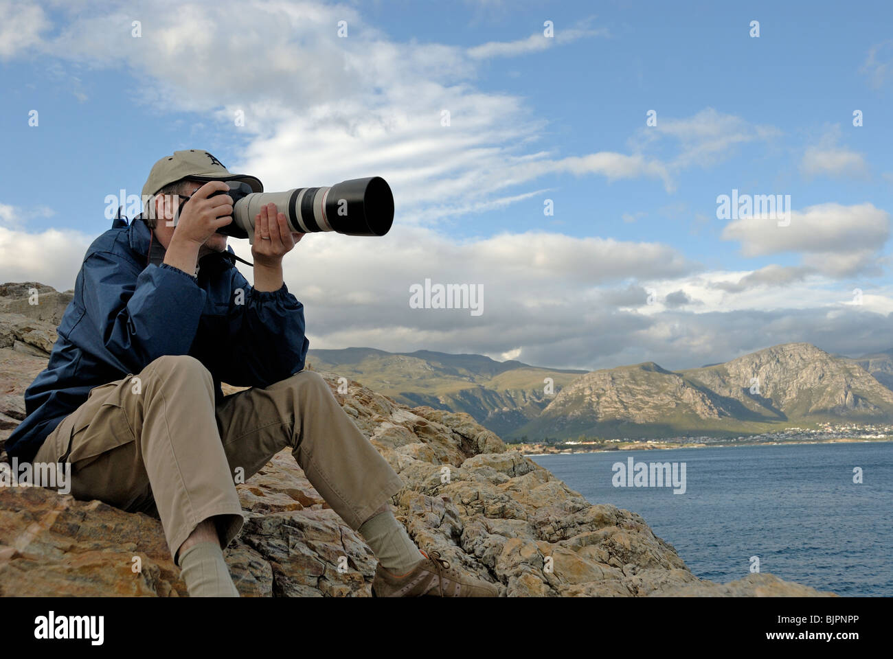 L'uomo fotografo scattare una fotografia di un paesaggio con un teleobiettivo, South Western Cape, Sud Africa Foto Stock