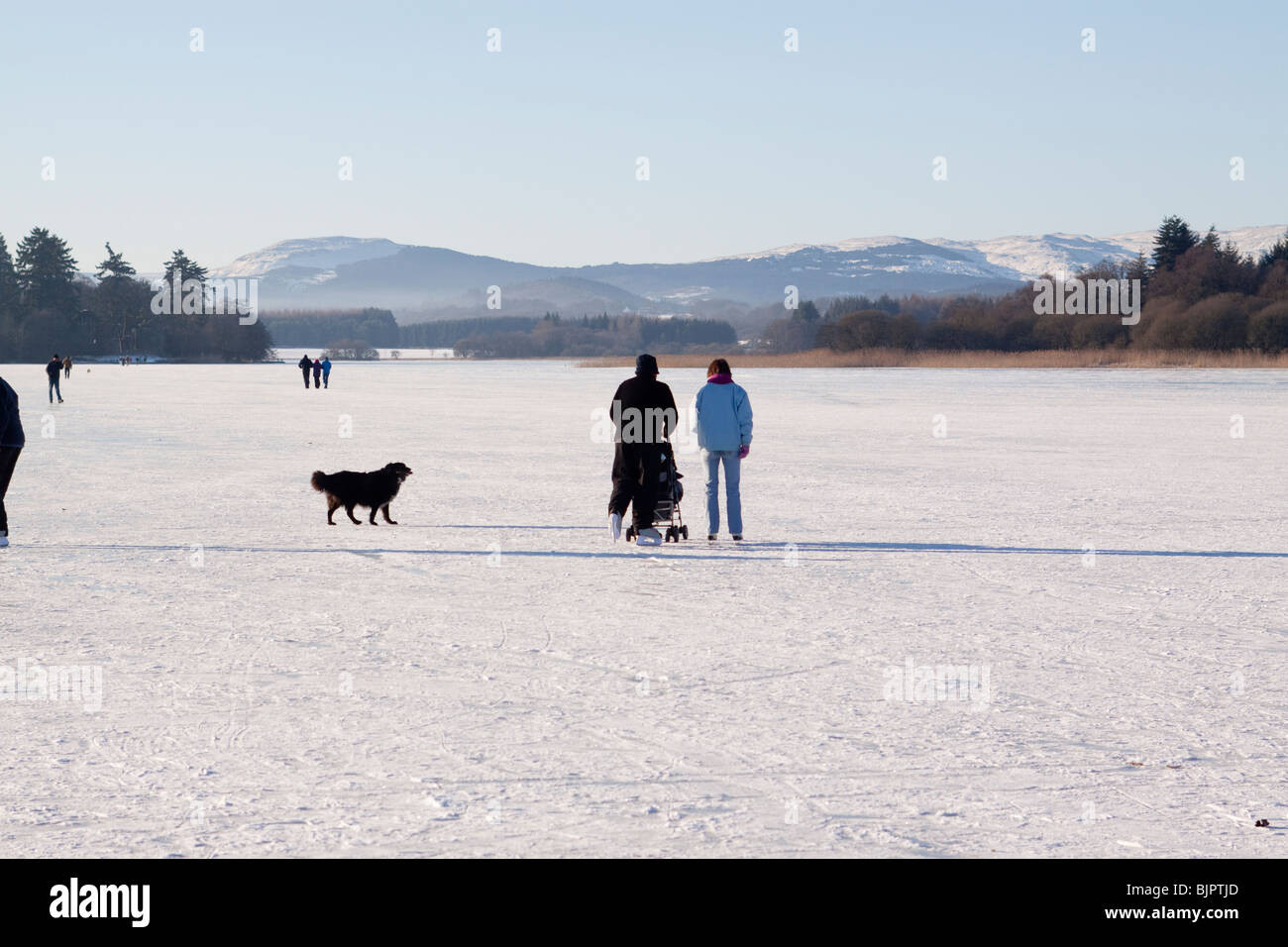 Pattinatore su ghiaccio spingendo la PRAM sul lago ghiacciato Foto Stock