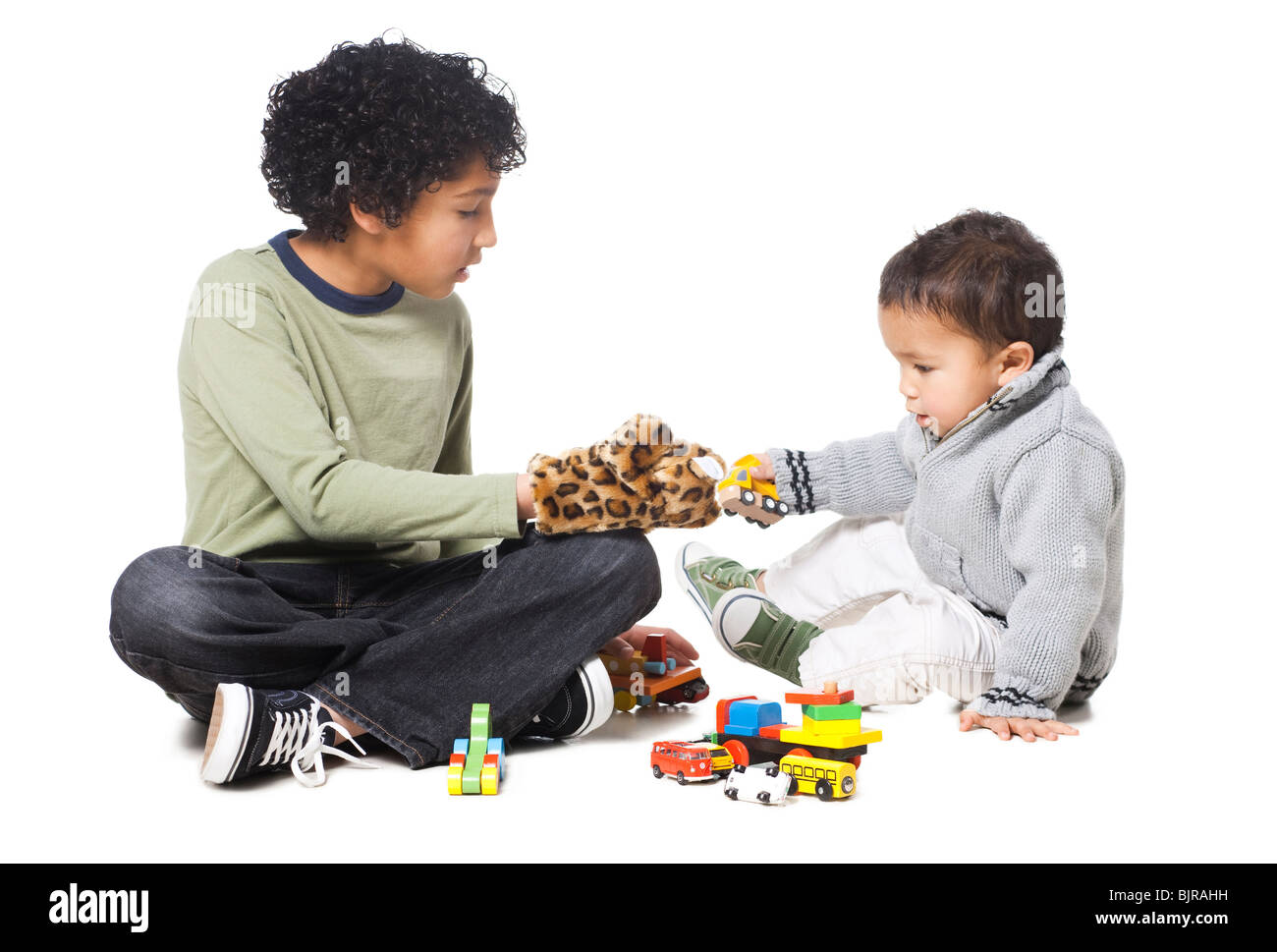 Fratelli (18-23 mesi) (8-9) giocando con giocattoli, contro uno sfondo bianco Foto Stock