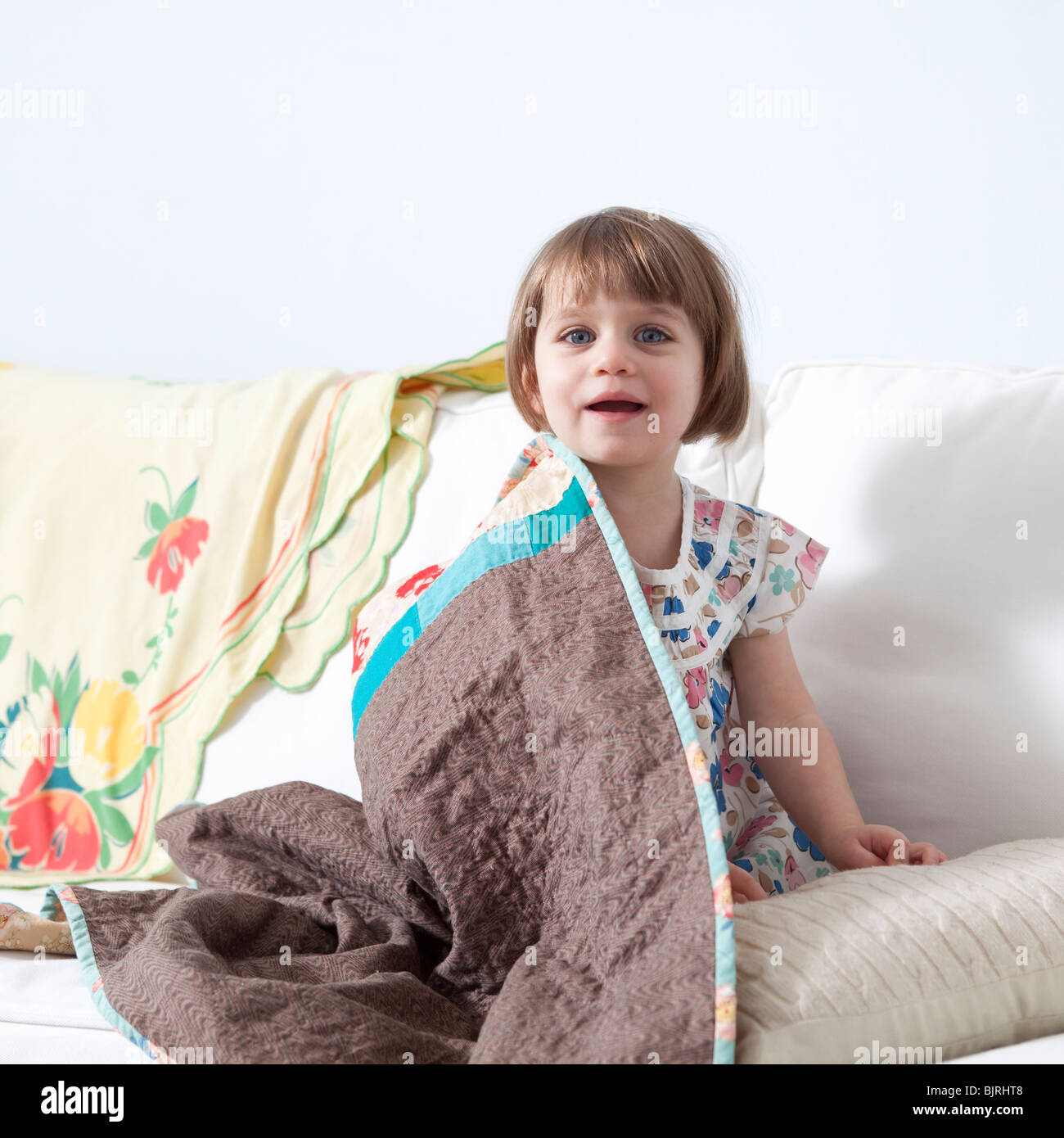 Stati Uniti, California, San Francisco, ragazza (2-3) seduto sul divano coperto con coperta Foto Stock