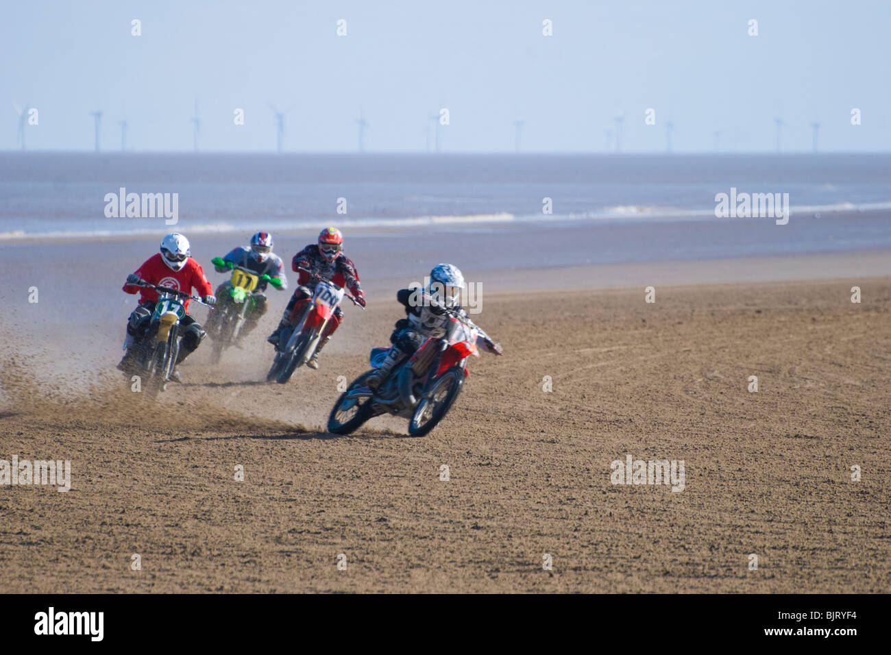 Moto Racing di sabbia sulla spiaggia con le turbine eoliche in background sul mare, Mablethorpe, Lincolnshire, England, Regno Unito Foto Stock