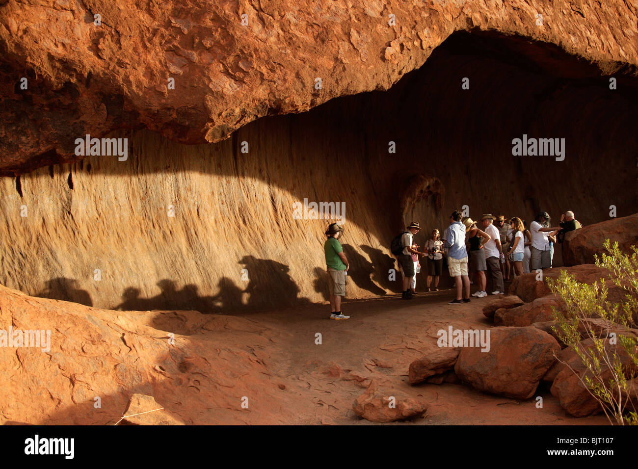 I turisti in una grotta di fama mondiale delle formazione di arenaria Uluru o Ayers Rock , Territorio del Nord, l'Australia Foto Stock