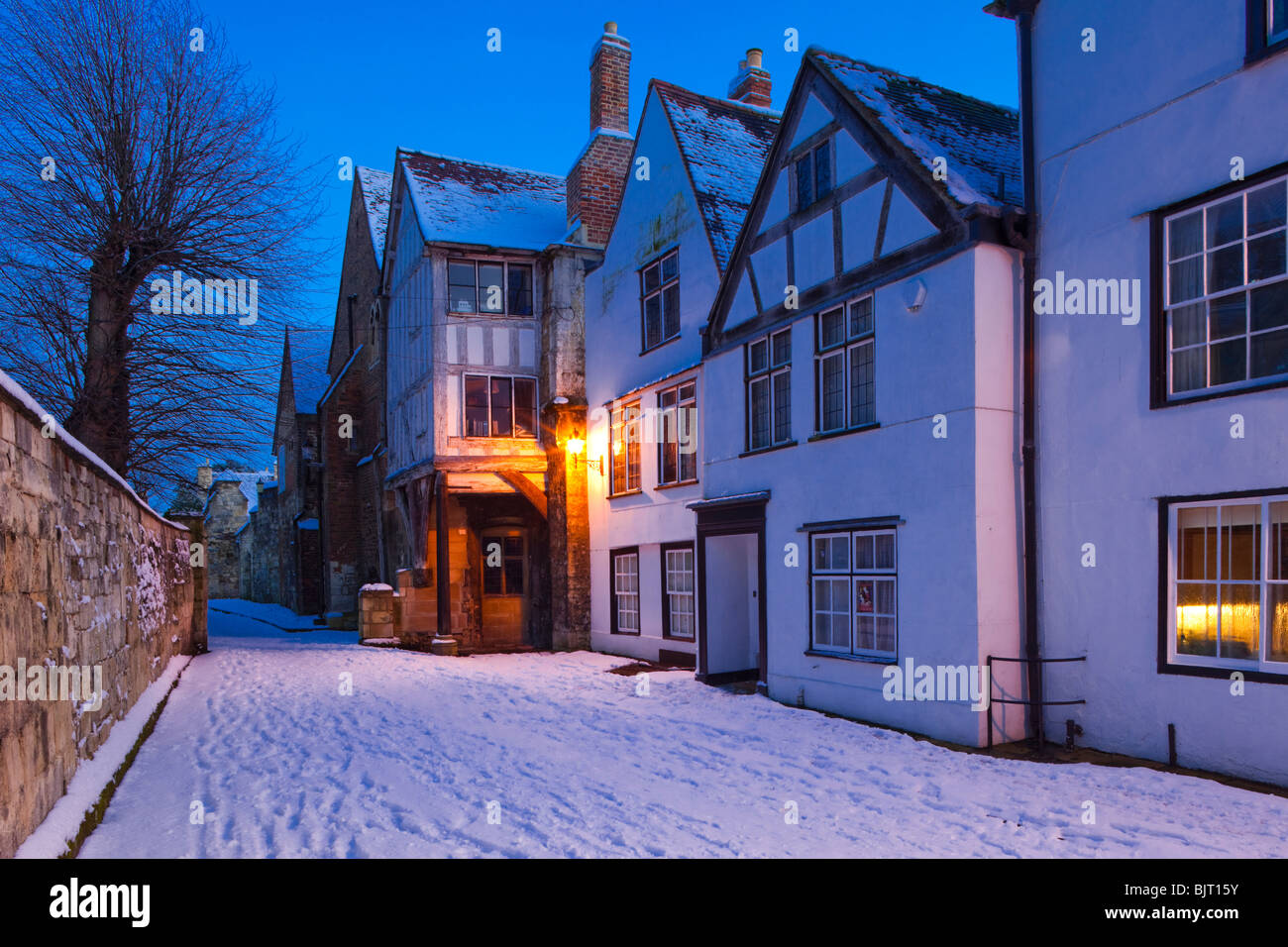 Tramonto sulla neve invernale e le case medioevali in mugnai verde accanto alla cattedrale di Gloucester Regno Unito Foto Stock