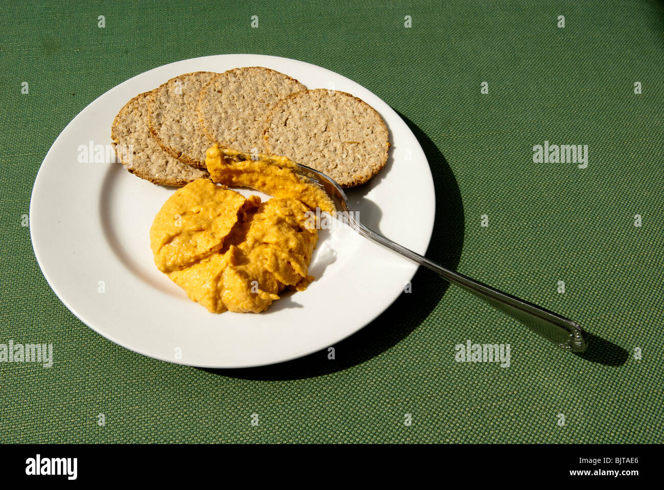 Una piastra di humus con biscotti di farina di avena e la forcella. Foto Stock