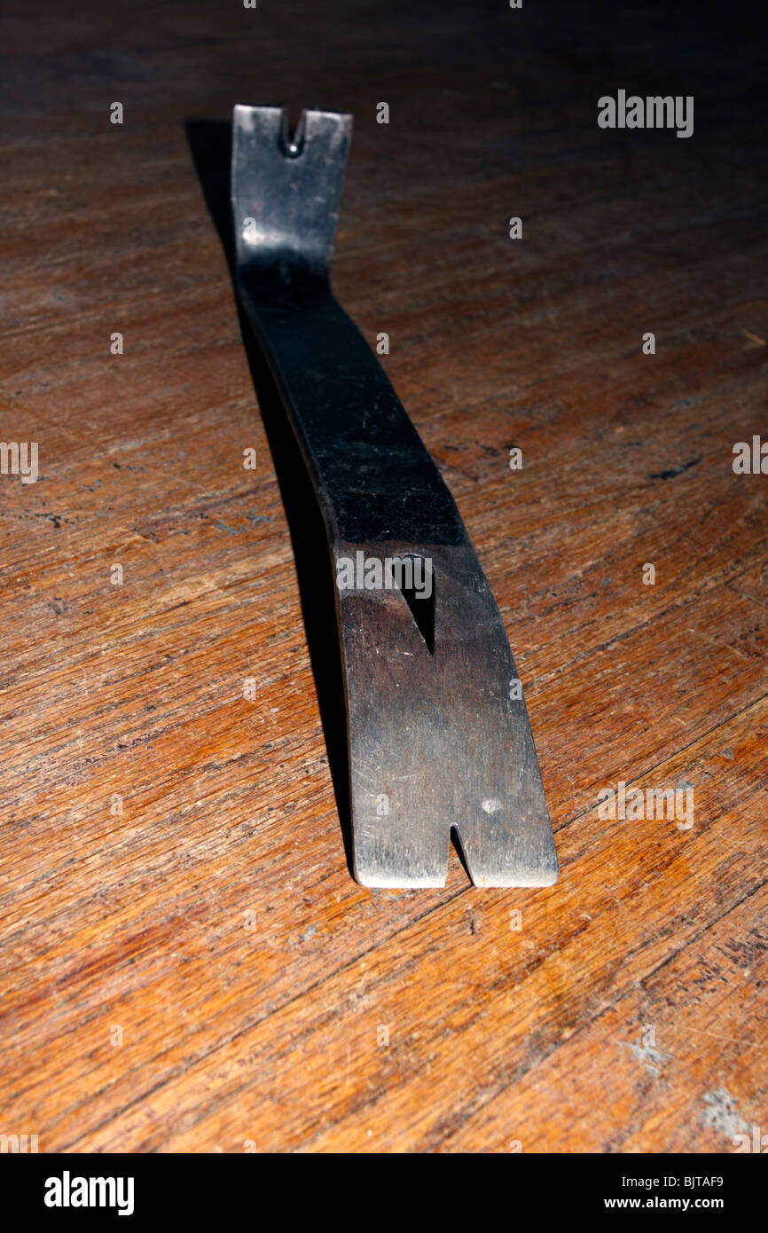 Standard in acciaio grezzo piede di porco o palanca, nero, sul legno polverosa superficie del pavimento, focus sulla punta. Foto Stock