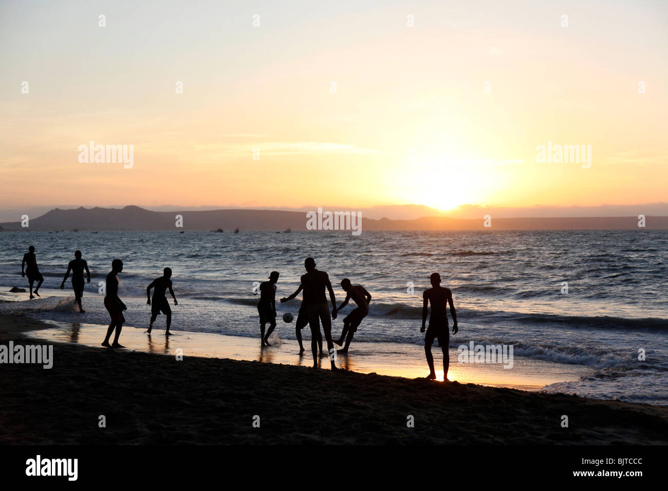 Gli amici che giocano a calcio sulla spiaggia al tramonto del sole. La città di Benguela beach, Angola. L'Africa. © Zute Lightfoot Foto Stock