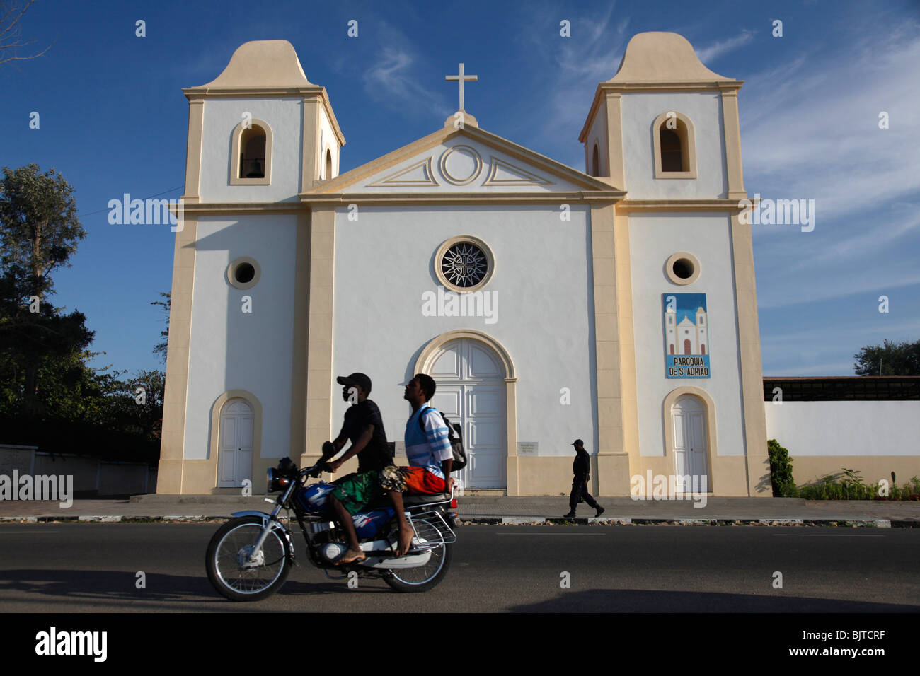 Gli adolescenti in un viaggio in moto passato una chiesa nella baia di Namibe, provincia di Namibe, Angola, Africa Foto Stock