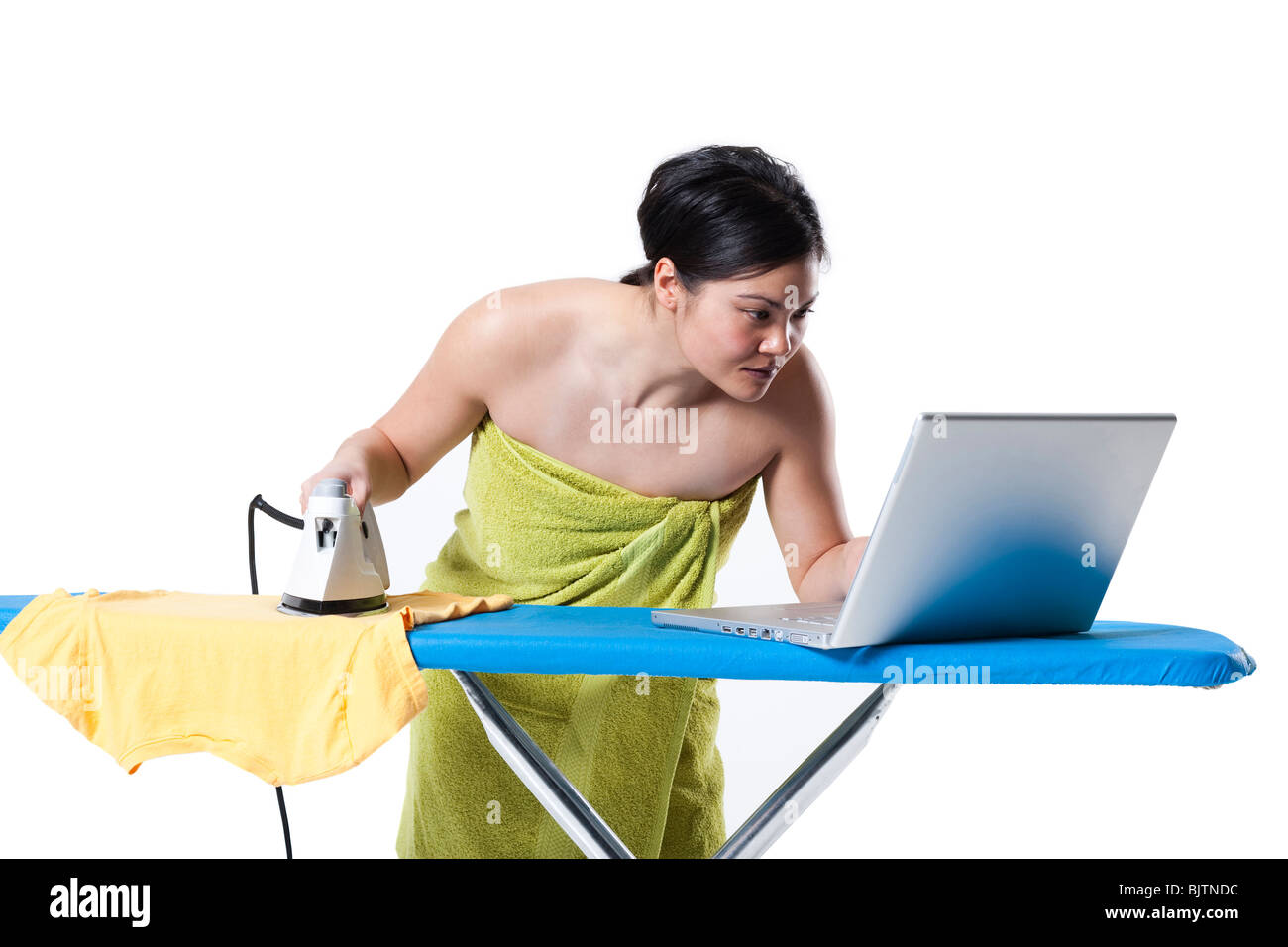 Donna di stiratura e di lavorare sul computer portatile Foto Stock