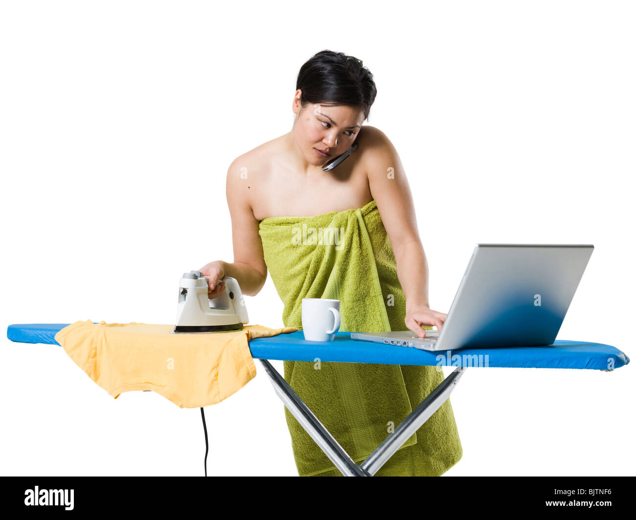 Donna di stiratura e di lavorare sul computer portatile Foto Stock