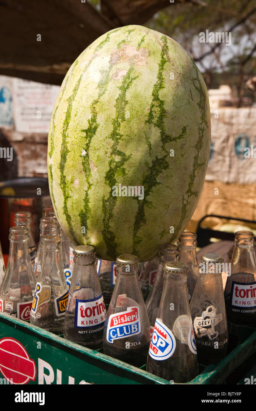India Kerala, Palakkad, snack stradale del venditore di anguria di stallo bilanciato sulla sommità di soda di bottiglie di acqua Foto Stock
