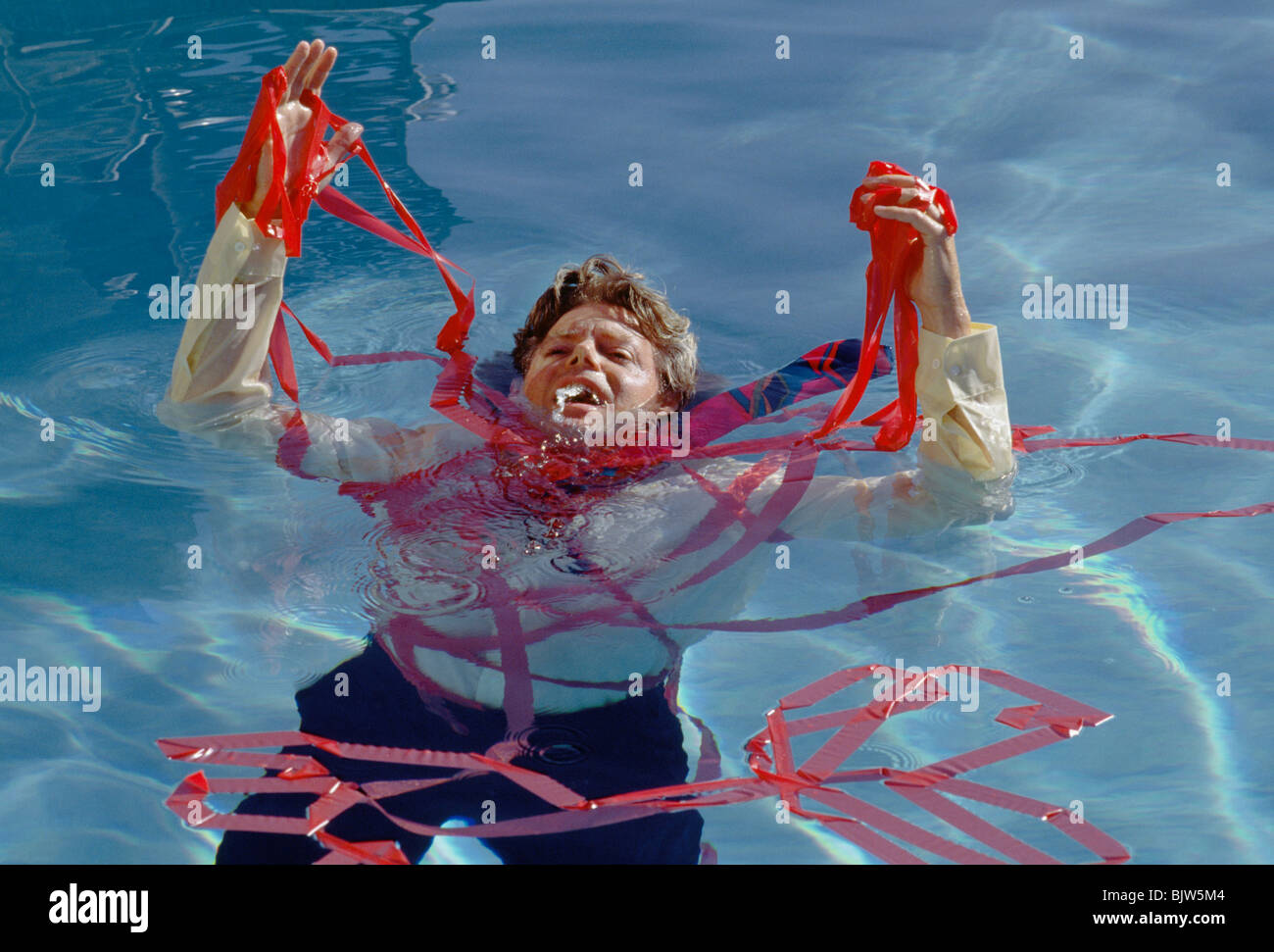 Uomo che annega nel nastro rosso Foto Stock