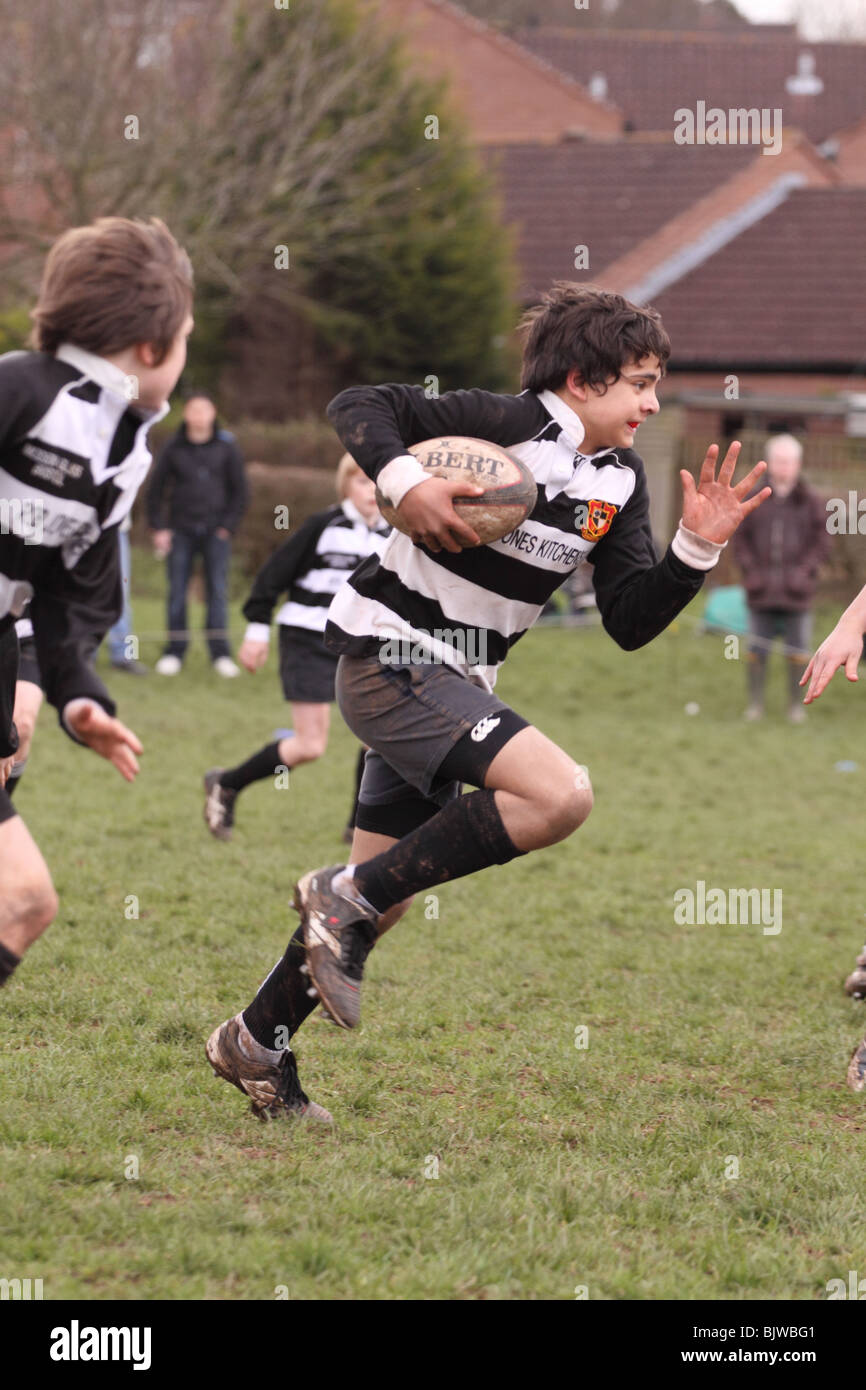Junior rugby giovani giocatori in competizione club match in esecuzione con la palla solo uso editoriale Foto Stock