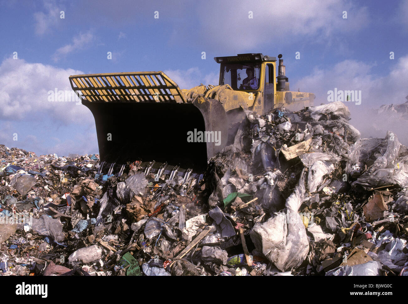 Garbage è diffusa da una benna caricatore in un sito di discarica in Bitterfelt, Germania. Foto Stock