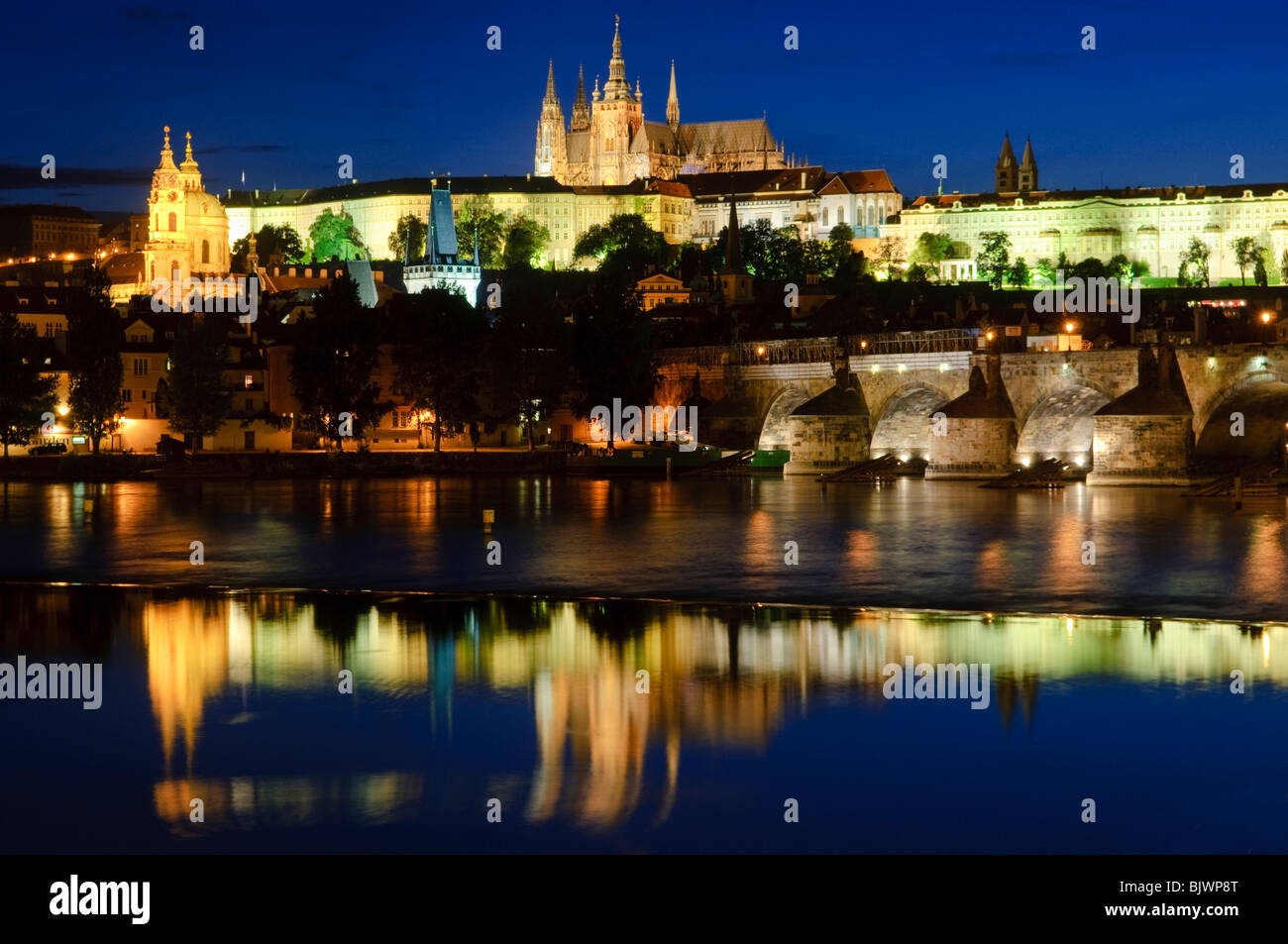 PRAGA, Repubblica Ceca - il Castello di Praga si riflette sul fiume Moldava con il Ponte Carlo sulla destra. L'iconico Castello di Praga, simbolo della storia e del potere della Repubblica Ceca, sorge maestosamente su una collina che domina la città. È il castello antico più grande del mondo e un sito patrimonio dell'umanità dell'UNESCO, che attira ogni anno innumerevoli visitatori per esplorare la sua affascinante storia e la sua diversità architettonica. Foto Stock