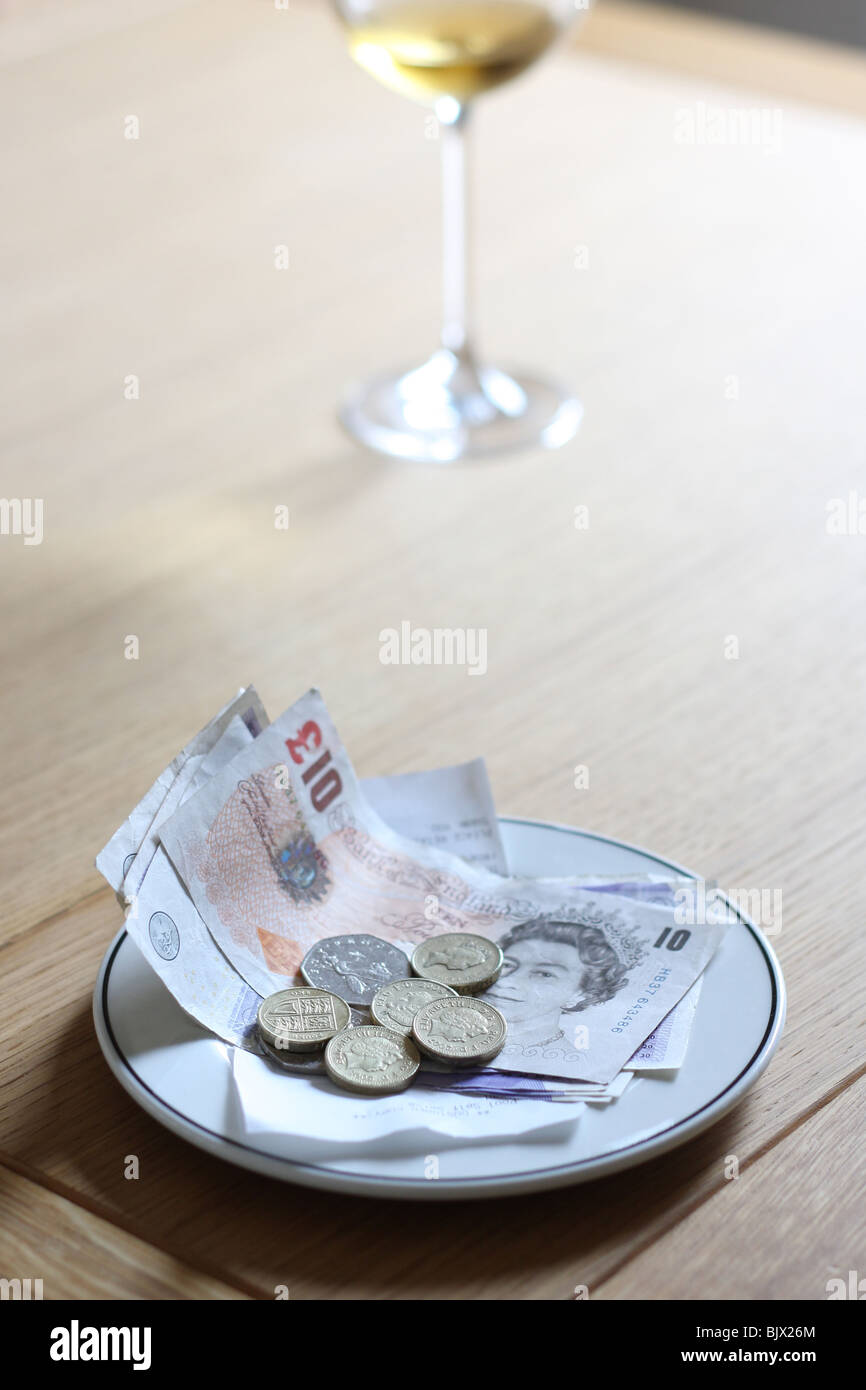 Una fattura pagata presso un ristorante accanto a un bicchiere di vino. Foto Stock