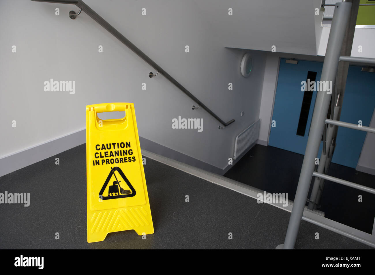 Attenzione: pulizie in segno di progresso nella parte superiore di un gruppo di scale in un edificio moderno Foto Stock