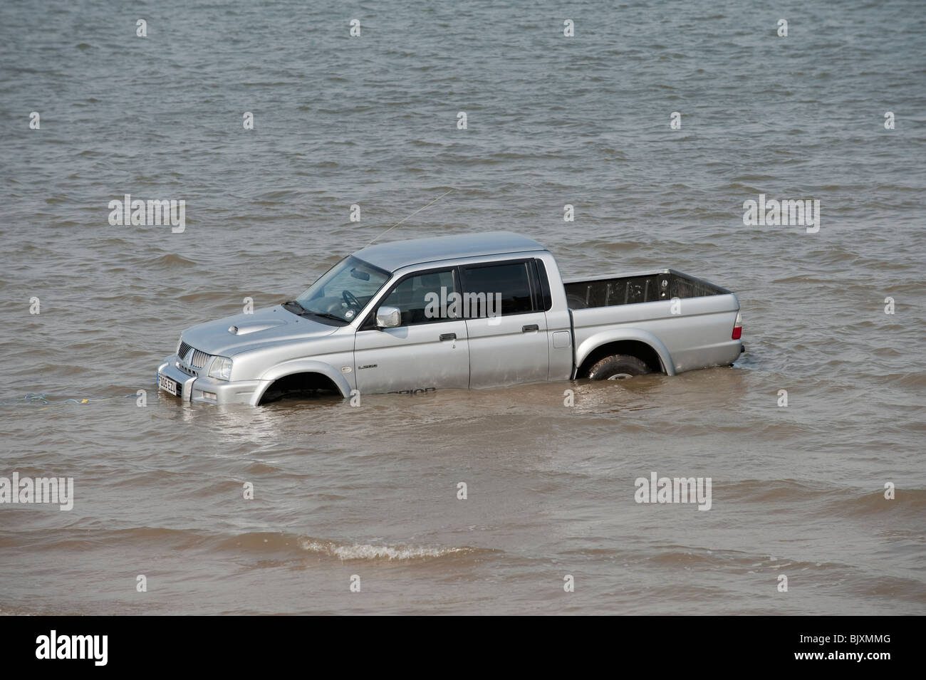 Auto / carrello / SUV bloccato in morbida sabbia sulla spiaggia con marea Foto Stock