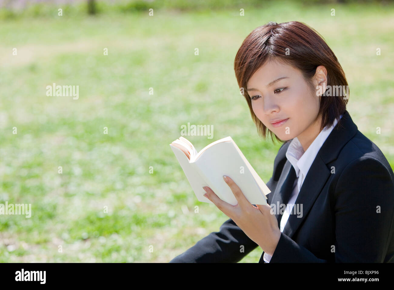 Giovane imprenditrice leggendo un libro in un parco Foto Stock