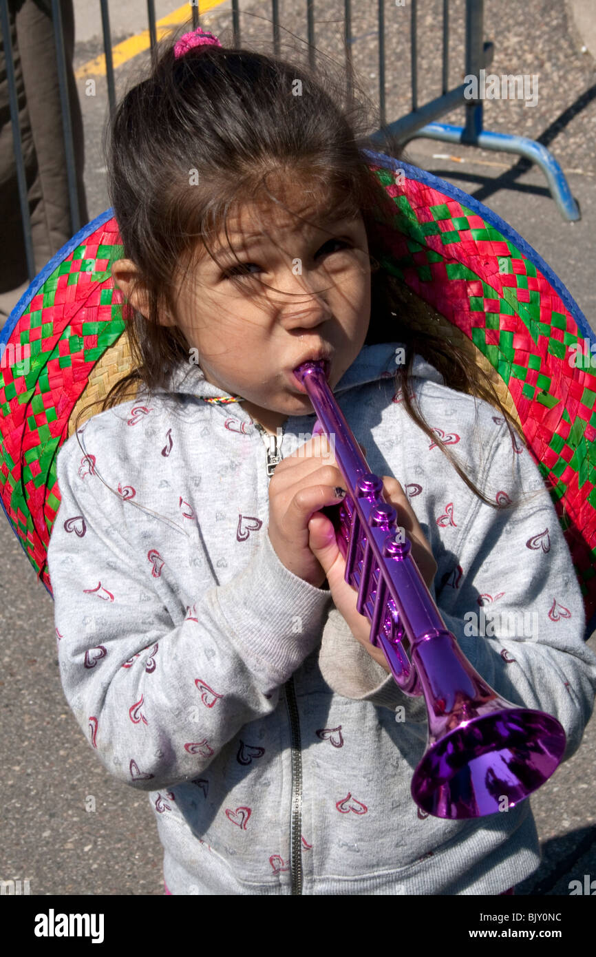 Ragazza ispanica età 5 soffiaggio tromba giocattolo in parata. Cinco de Mayo Fiesta St Paul Minnesota USA Foto Stock