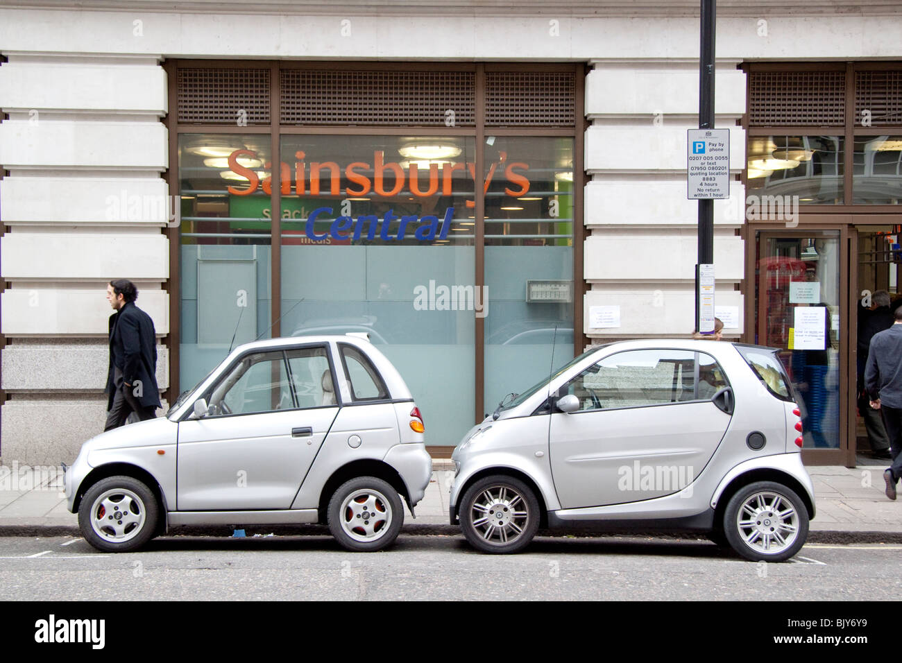 Due piccole automobili, elettrico G-Wiz a benzina e Smart auto parcheggiate la condivisione di un unico spazio di parcheggio nella zona di Mayfair di Londra. Foto Stock