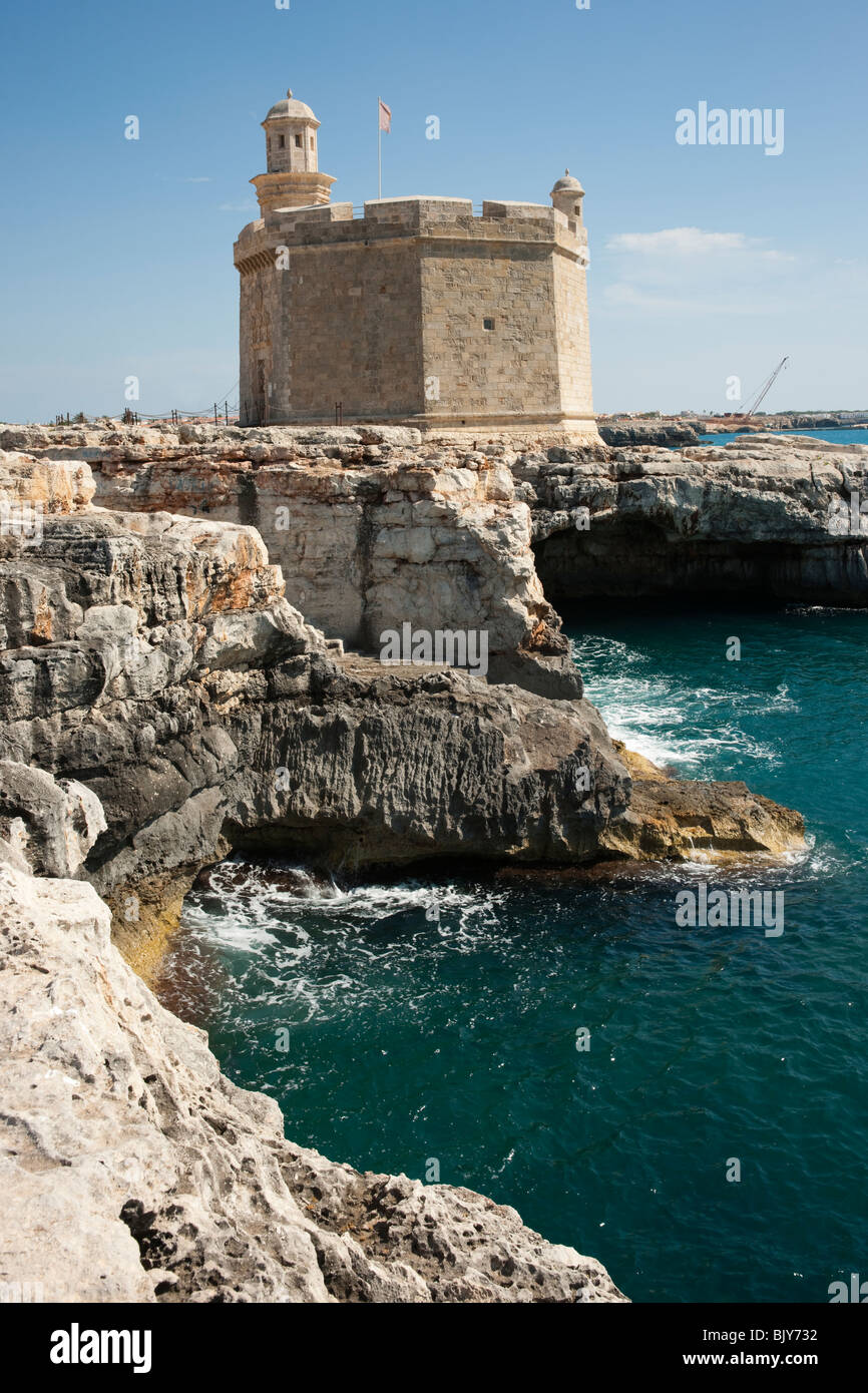 Vecchia torre fortezza sulle rocce dal mare contro il cielo blu, Ciutadella de Menorca, Menorca, Spagna Foto Stock